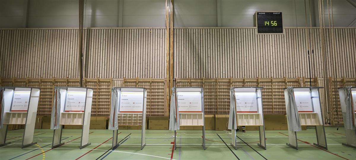 Valget 2021. Bildet viser valgavlukker i en gymsal, på rekke og rad. - Klikk for stort bilde