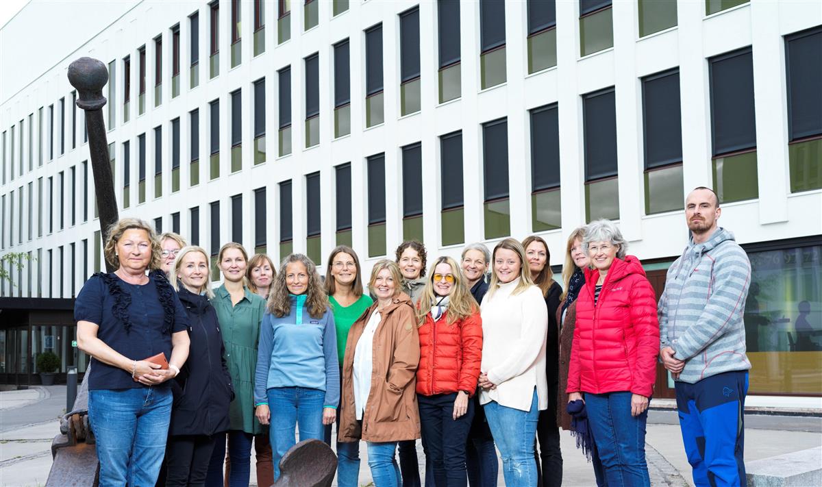 Gruppebilde av ansatte i enhet Forebyggende helsetjenester. De ansatte står på rekke og rad utenfor K49 i sentrum av Narvik, og man ser bygningen i bakgrunnen. - Klikk for stort bilde