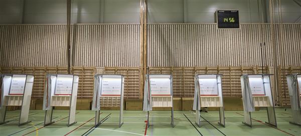 Valgbåser i en gymsal på rekke og rad.